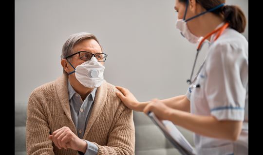 Masked patient and masked nurse in conversation