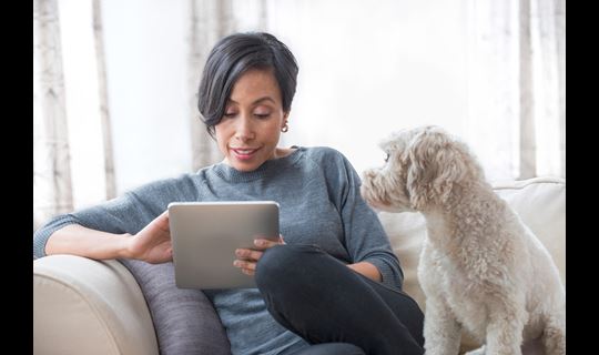 Black woman with small dog looks at tablet